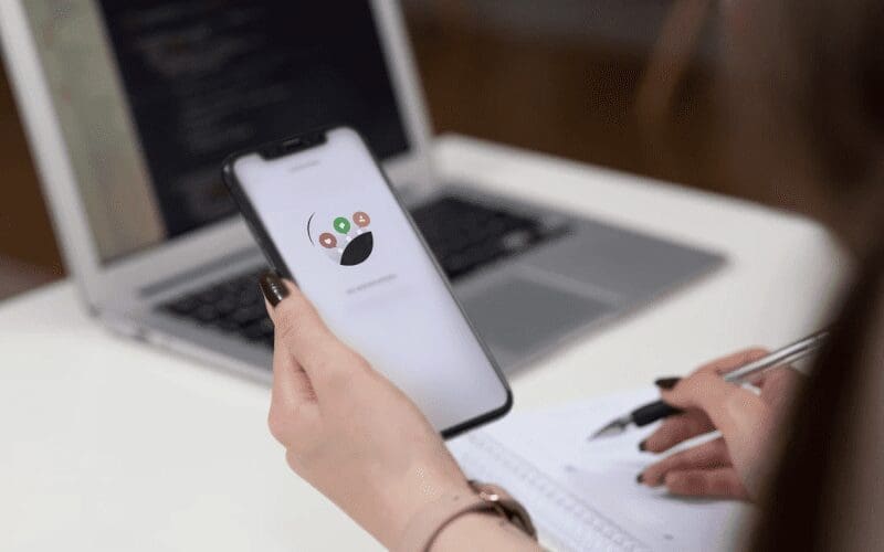 A lady holding a phone while taking notes.