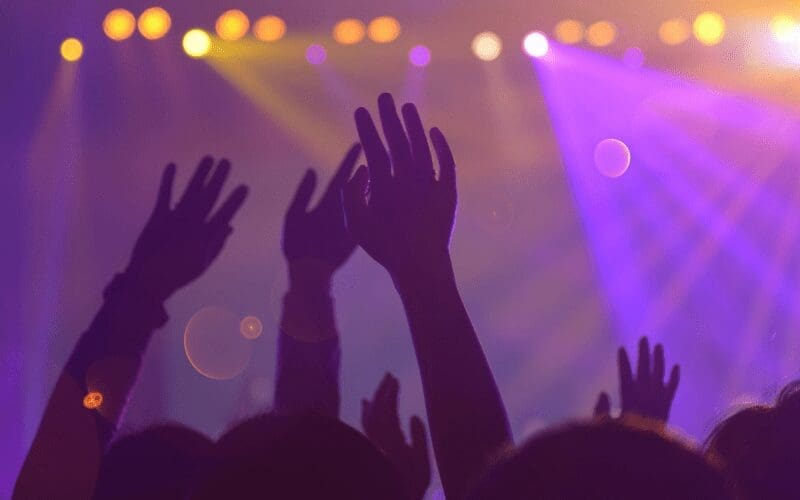 People at Amsterdam dance event doing hand signs in the crowd.